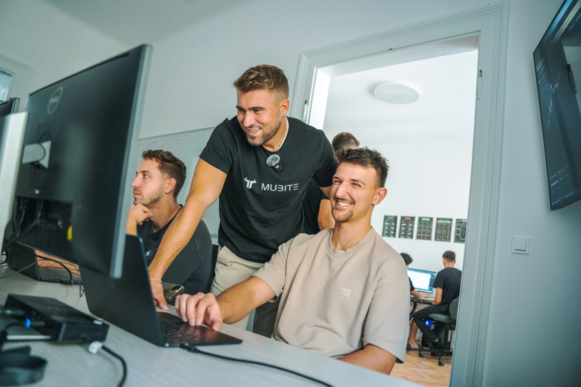 A trader setting up at a laptop with a Mubite team member at the Prague live tournament